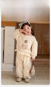 Detail showing beige knitted cotton sweatshirt with floral pocket and ruffle hem for toddlers