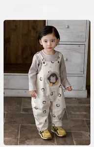 Close-up of toddler overalls featuring a large penguin patch and snap button straps