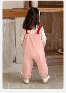 Détail d'une blouse florale et d'une salopette rose pour bébé fille avec chevilles élastiques