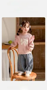 Détail du sweat-shirt rose avec nœud et ensemble de pantalon en jean à dentelle