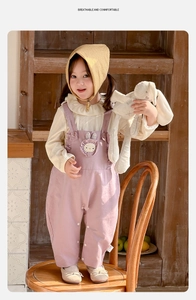 Détail d'une tenue de fillette avec chemise à col volanté et salopette lapin