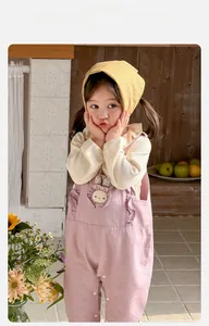 Détail de la salopette rose pour bébé avec broderie lapin et haut rayé beige