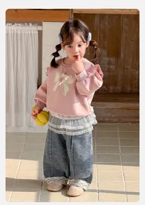 Détail du sweat rose pour bébé avec bordure en dentelle et nœud avec pantalon denim