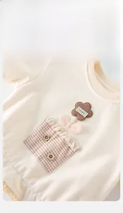 Close-up of cream baby sweatshirt featuring lovely floral embroidery and plaid pocket