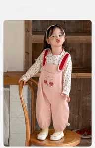 Détail de la salopette rose pour bébé avec lapin et bretelles volantées sur chemise