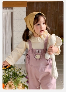 Détail d'une tenue de bébé fille avec broderie lapin sur une salopette rose et un haut