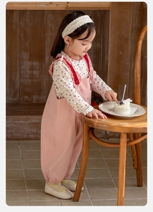 Détail d'une salopette en velours rose pour filles avec volants et chemise à fleurs à manches