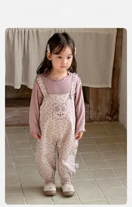 Detail of pink ruffled collar top and beige floral overalls with bunny embroidery