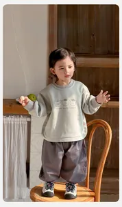 Detail of baby boys outfit with green bear sweatshirt and grey joggers on toddler