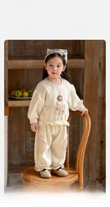 Detail view of beige knit toddler set with 3D flower applique and plaid patchwork