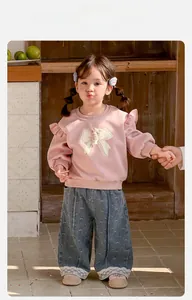 Détail du sweat rose à manches longues avec ours 3D et jean à bords en dentelle pour fille