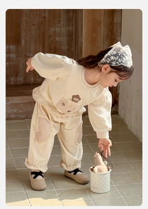Detail of cream toddler tracksuit with floral patch, plaid pocket and ruffled leg cuffs