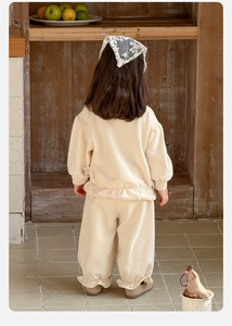 Detail view of cotton two-piece baby outfit with ruffled hems and matching headscarf