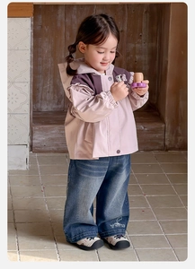 Detailed view of kids windbreaker with purple panels and wide leg jeans on wooden background