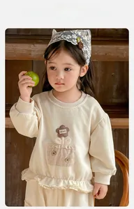 Detail of baby floral knit outfit showing handmade applique and lace trim on beige sweater