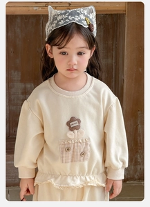 Detail of baby girl cream sweatshirt featuring floral applique and lace hem details
