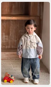 Detail einer Jungen Windjacke mit Kapuze im Color-Block Design und blauen Jeans