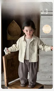 Close-up of baby beige jacket and brown pants with Pig Bus pattern for spring