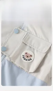 Detail der Patchwork-Windjacke für Jungen mit Bärenstickerei und Druckknopftaschen