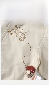 Detail of baby cotton shirt featuring Pig Bus print and a 3D checkered mushroom patch