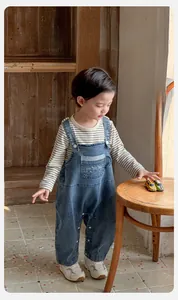 Détail de salopette en jean pour bébé avec haut rayé sur sol en bois rustique