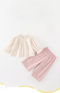 Detail of floral baby girl blouse with ruffled collar and pink trousers set