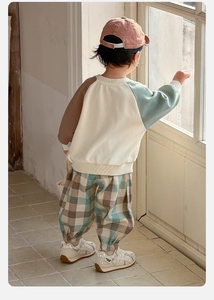 Détail d'une tenue de printemps pour bébé avec sweat-shirt patchwork et pantalon à carreaux