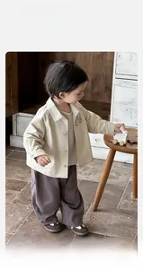 Detail of baby casual cotton set with cartoon car jacket and wide-leg brown trousers