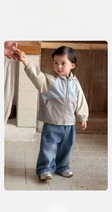 Détail de la veste coupe-vent pour bébé garçon avec blocs de couleurs et jean brodé