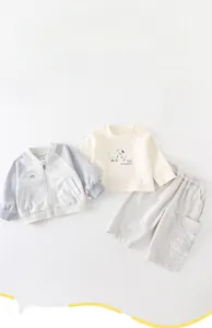 Détail à plat d'un ensemble 3 pièces pour bébé avec motif chien et veste zippée