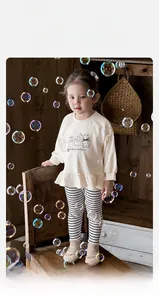 Detail of baby girl beige sweatshirt with cartoon print and striped leggings outfit
