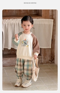Détail de l'ensemble printemps bébé montrant le sweat patchwork et le pantalon à carreaux