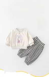 Close-up of baby spring outfit set with cream sweatshirt and striped pants