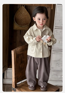 Detail of baby beige long sleeve shirt with Pig Bus print and cotton trousers