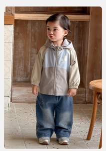 Détail de la veste coupe-vent à capuche pour bébé et du jean large à blocs de couleurs