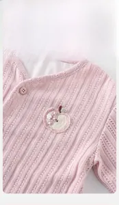 Detail der rosa Baby-Strickjacke mit Apfelstickerei und strukturierter Baumwolle