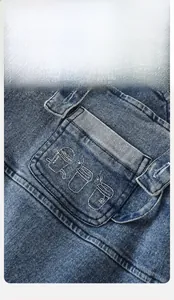 Détail de la salopette en jean pour bébé avec broderie de tasses et coutures de qualité