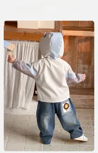 Detail der Jungen-Farbblockjacke und Jeans mit niedlichem Löwen-Aufnäher an der Gesäßtasche