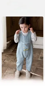Detail of baby denim overalls with sun and crocodile embroidery and striped t-shirt