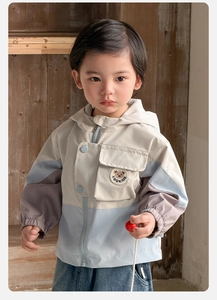Detail der winddichten Kapuzenjacke mit Farblock-Design und Bärchen-Patch