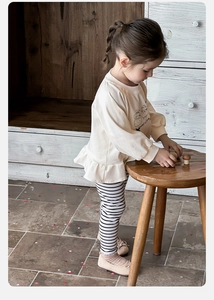 Detail of baby girl cotton set featuring ruffle top with sheep print and striped leggings