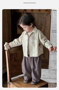 Detail of baby cotton set featuring a beige shirt with Pig Bus print and brown trousers