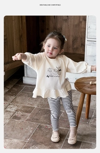 Detail of baby girl two-piece set featuring cream sweatshirt and striped leggings