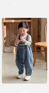 Détail d'un ensemble salopette en jean pour bébé avec un t-shirt rayé à la maison