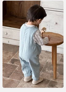 Detail of baby boy light blue denim overalls with vertical back stitching and cotton texture