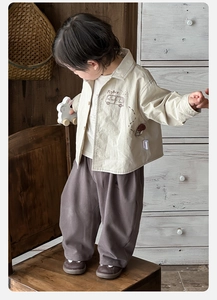 Detail of baby boy retro beige jacket and brown wide-leg pants set with bus print