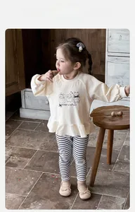Close-up of cotton baby set with cream sweatshirt featuring ruffle hem and striped leggings