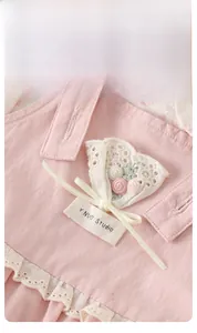 Close-up of pink cotton overall dress with 3D flower embroidery and lace details