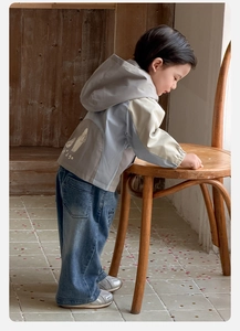 Détail d'un ensemble veste à capuche pour bébé avec motif au dos et jean bleu