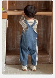 Vue arrière d'un bébé garçon portant une chemise rayée et une salopette en jean bleue